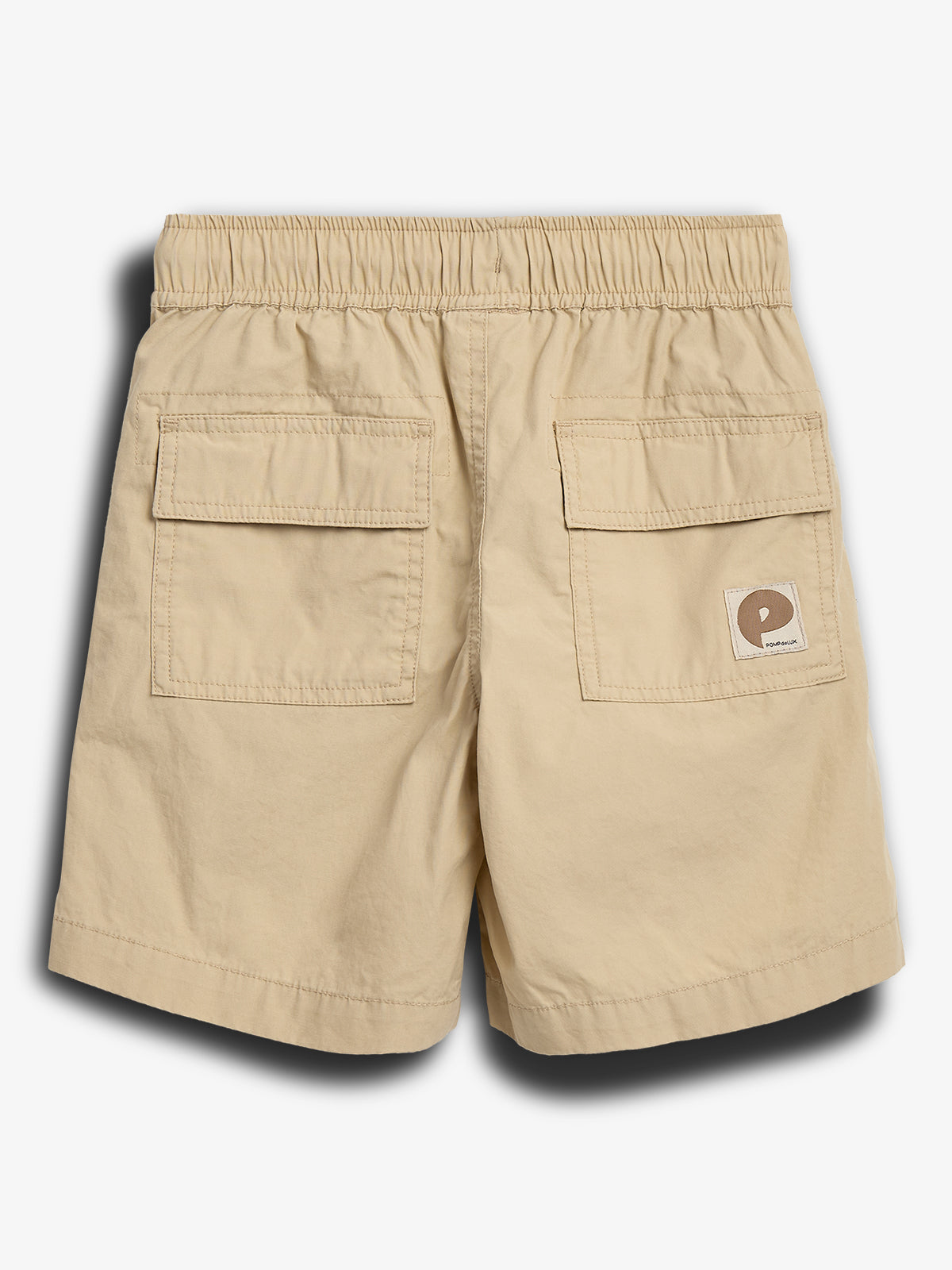 Beige Shorts mit elastischem Bund und zwei aufgesetzten Gesäßtaschen; ein kleines Logo-Etikett mit dem Text "POP TRADING COMPANY" befindet sich auf der rechten Tasche; Hintergrund ist weiß.