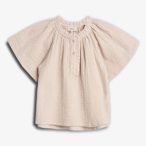 A cream-colored, short-sleeved baby blouse hangs in a white background. The blouse features a gathered neckline, button closure, and loose, textured fabric, creating a casual and comfortable look.