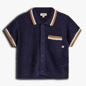 A navy blue knitted short-sleeve shirt with button closure is presented on a plain background. It features a textured pattern, pocket with beige accents, and a label reading "puma kids."