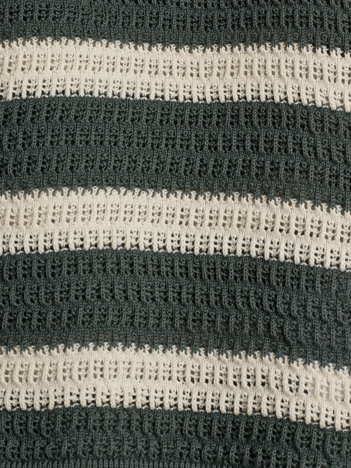 Gestrickter Stoff mit horizontalen Streifen in dunkelgrau und creme. Die Struktur ist durchbrochen und wiederholt sich gleichmäßig, erzeugt ein regelmäßiges Muster.