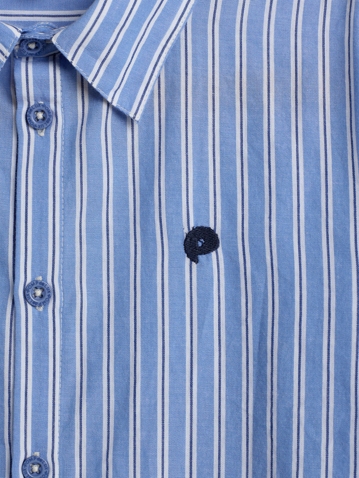 A blue and white vertically striped button-up shirt with a small dark emblem on the chest, displayed against a neutral background. Buttons feature the text "Luxire Custom Clothing."