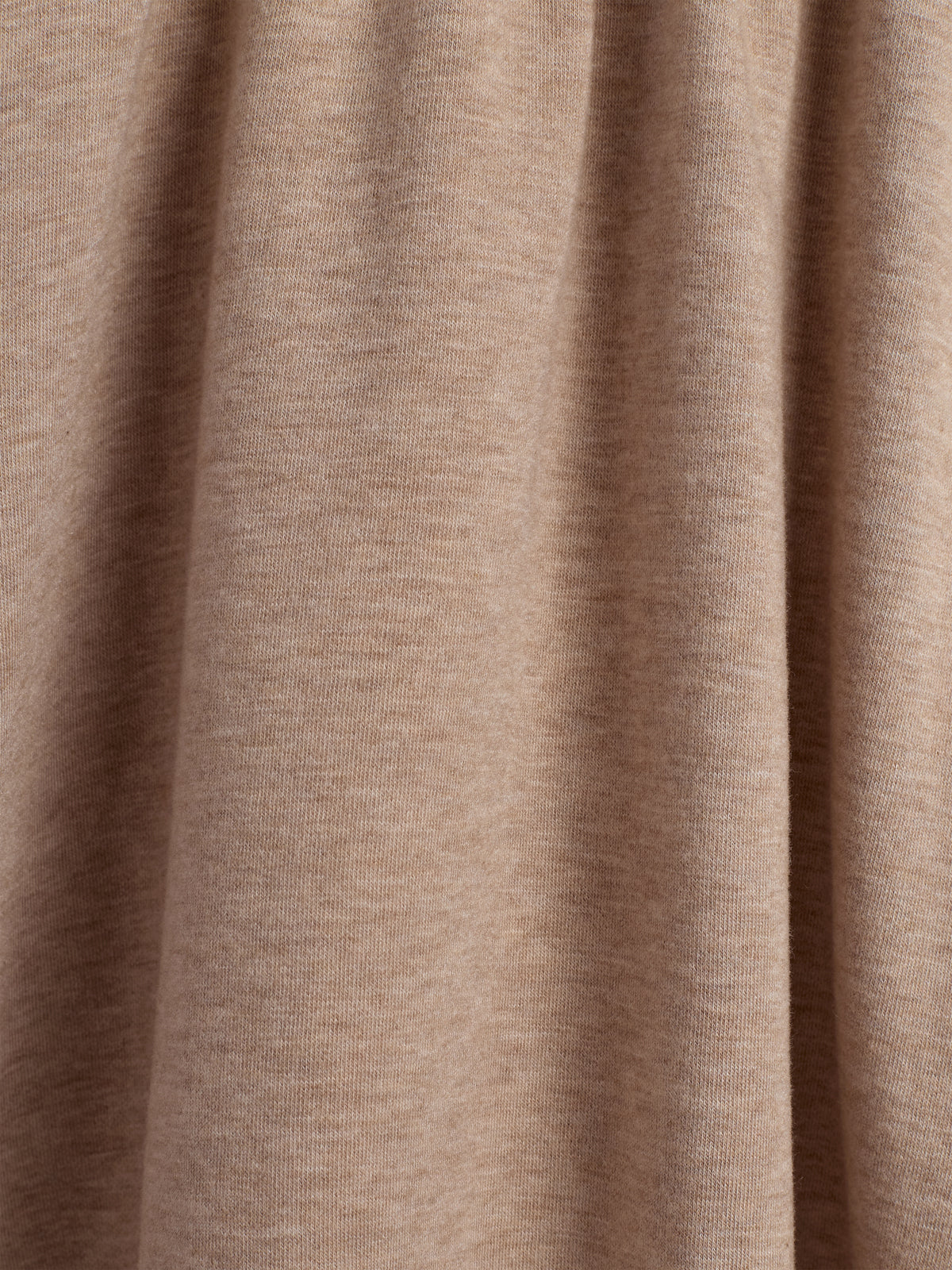 Ein hellbrauner Stoff hängt in sanften Falten. Die texturierte Materialoberfläche zeigt feine Fasern und Schatten. Der Hintergrund ist neutral und schlicht.