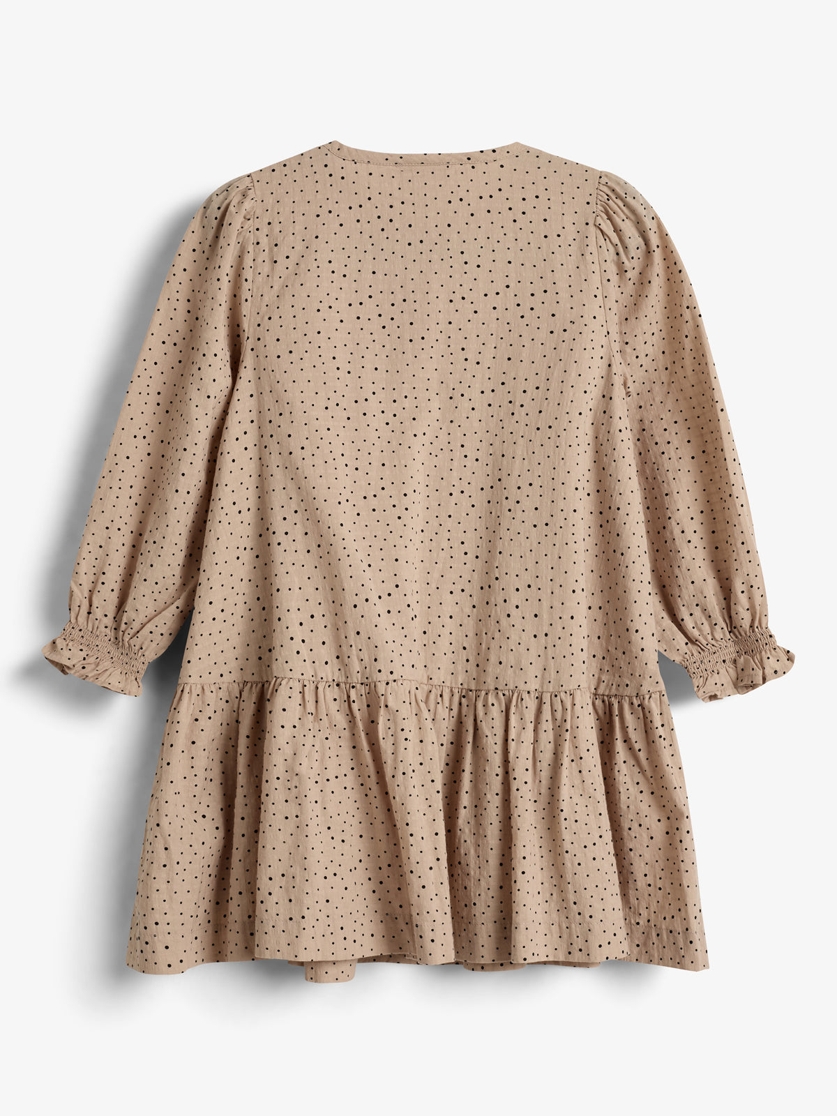 Beigefarbenes Kleid mit schwarzen Punkten, langen Ärmeln und Rüschen. Die Struktur wirkt leicht und fließend. Es liegt flach auf einem weißen Hintergrund.