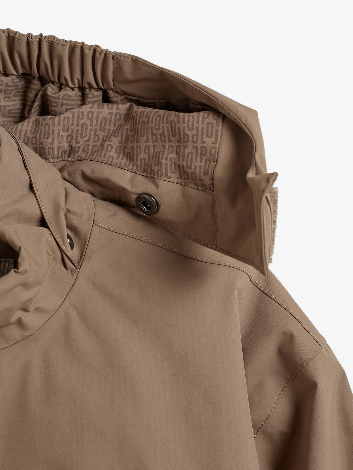 Eine braune Jacke mit Kapuze zeigt das Innenfutter mit wiederholtem Schriftzug "db". Der Kragen hat einen Knopf und elastische Bündchen. Der Hintergrund ist neutral gehalten.