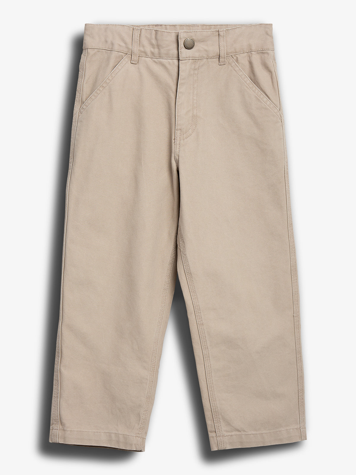 Beige Hose liegt flach auf einem einfarbigen Hintergrund. Sie hat seitliche Eingrifftaschen, Gürtelschlaufen und einen Knopfverschluss. Die Hose ist für Kinder geeignet und präsentiert sich schlicht.