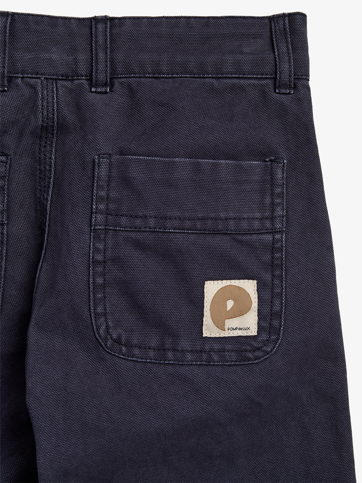 Eine dunkelblaue Hose mit aufgesetzter Gesäßtasche, die das Logo "POMPEIUX" auf einem beigen Etikett zeigt, liegt flach auf weißem Hintergrund.