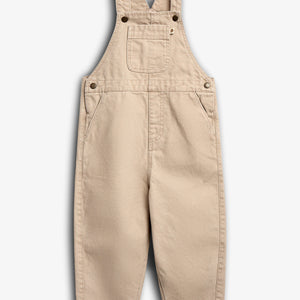 Latzhose in Beige liegt flach auf weißem Hintergrund. Sie hat verstellbare Träger, Seitentaschen und eine kleine Brusttasche. Kontextlos dargestellt, ohne erkennbare Marken oder Text.