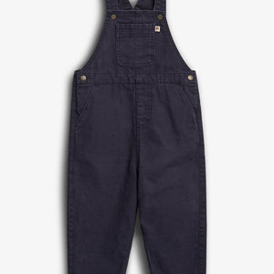 Dunkelblaue Latzhose liegt flach da. Sie hat verstellbare Träger, eine Brusttasche und seitliche Taschen. Der Hintergrund ist einfarbig weiß.