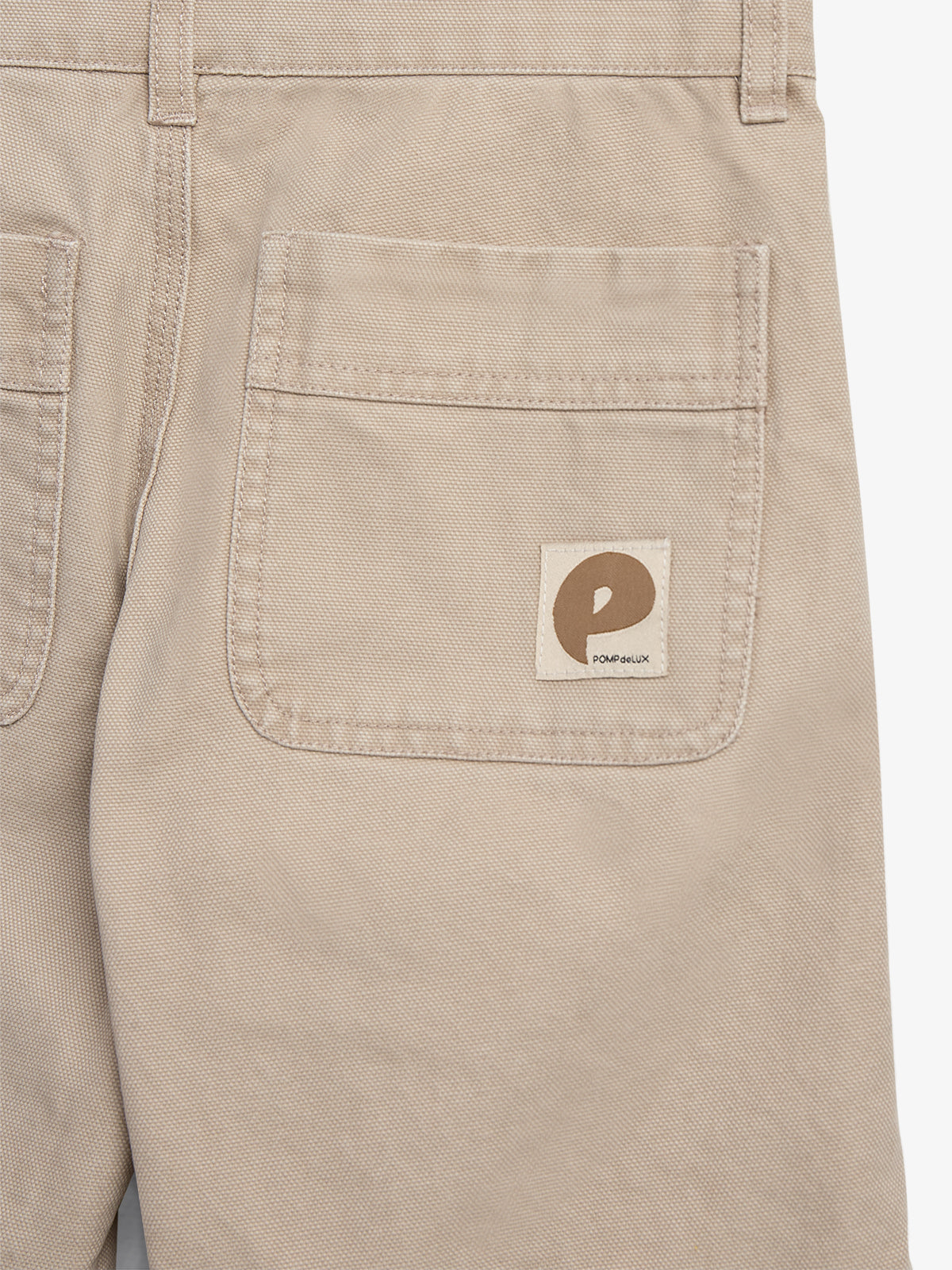 Beige Hose mit großer Tasche, zeigt ein aufgenähtes Emblem mit dem Buchstaben "P". Die Marke "POMPEIUX" ist auf dem Etikett vermerkt.