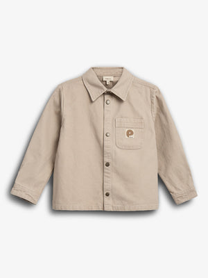 Beige Hemdjacke mit Knopfleiste und Kragen, Taschenlogo links. Im Studio auf neutralem weißem Hintergrund fotografiert. Text im Label: "Polarn O. Pyret".