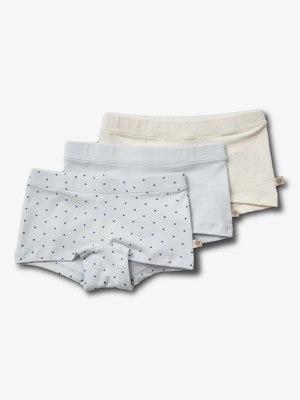 Drei Kinderunterhosen sind gestapelt; die vordere ist blaugrau mit kleinen schwarzen Punkten, die mittlere ist hellblau einfarbig, die hintere beige mit blauen Punkten, auf weißem Hintergrund.