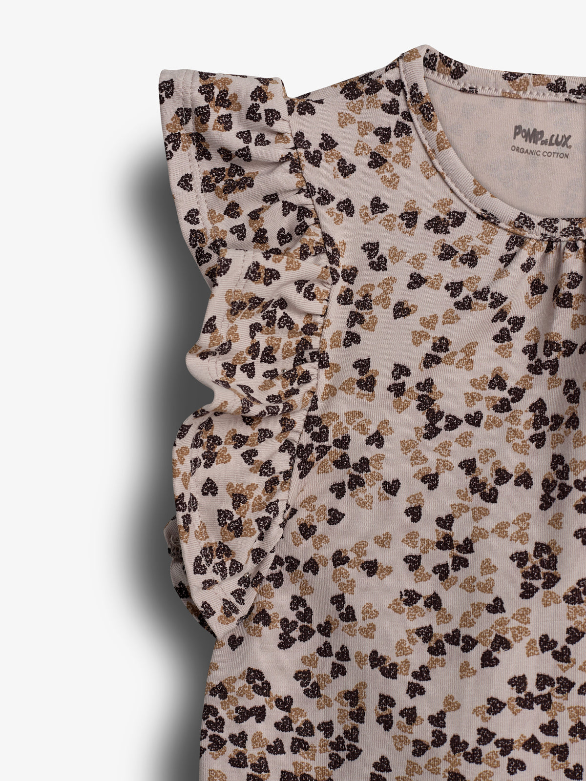 Ein Oberteil aus Bio-Baumwolle mit Rüschenärmeln, bedruckt mit braunen und schwarzen blattähnlichen Motiven. Text auf dem Oberteil: "Pom pelux ORGANIC COTTON". Der Hintergrund ist neutral.