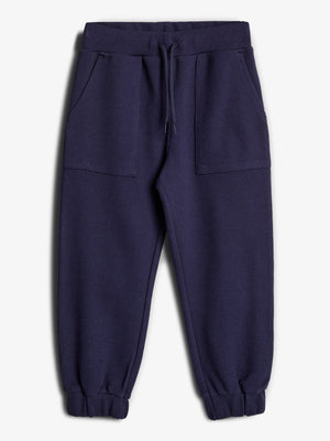 Dunkelblaue Jogginghose, liegt flach, mit einem Kordelzug im Bund, großen Taschen und gerippten Bündchen. Umgebung ist ein neutraler, heller Hintergrund.