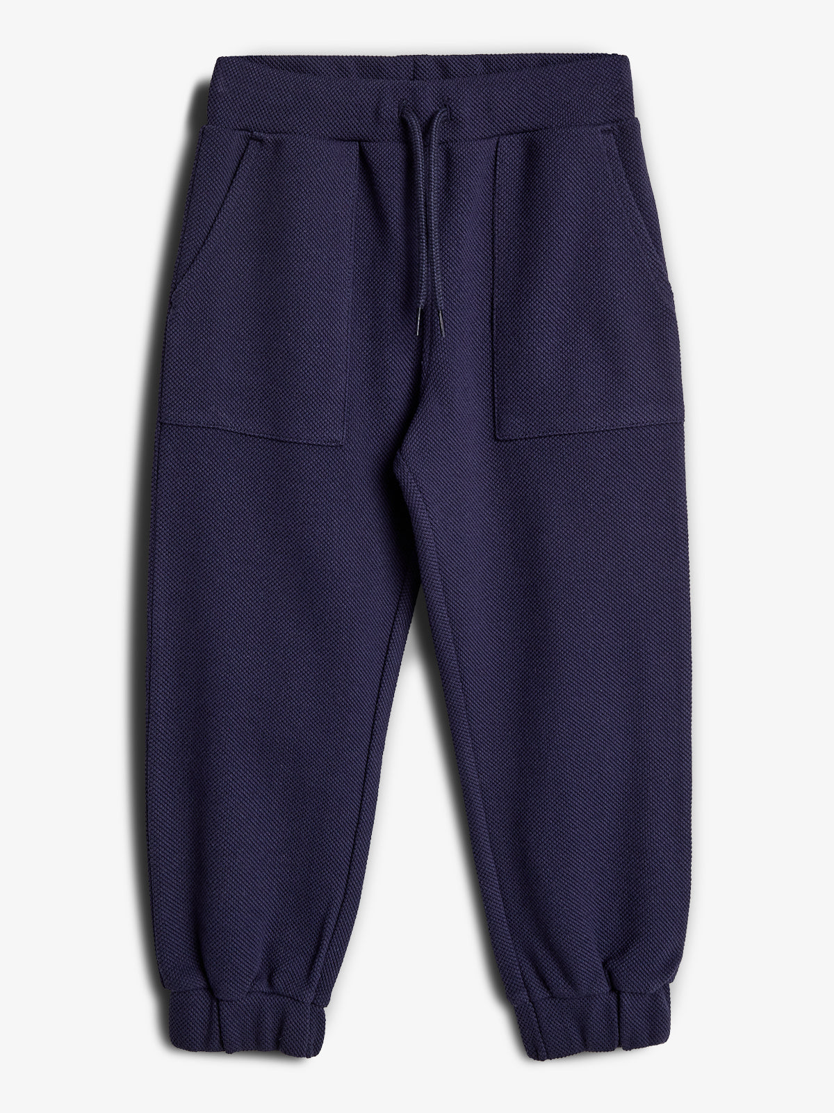 Dunkelblaue Jogginghose liegt flach auf einem weißen Hintergrund. Sie hat einen Kordelzug an der Taille, seitliche Taschen und elastische Bündchen.