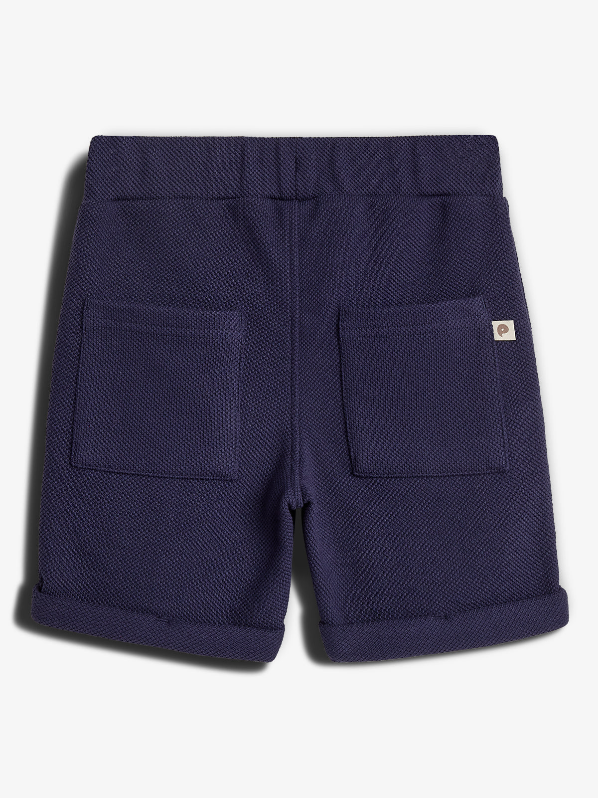 Dunkelblaue Shorts mit zwei aufgesetzten Taschen; ruht still auf weißem Hintergrund. Der Stoff hat eine strukturierte, gewebte Optik und ein kleines Etikett an der Seite.