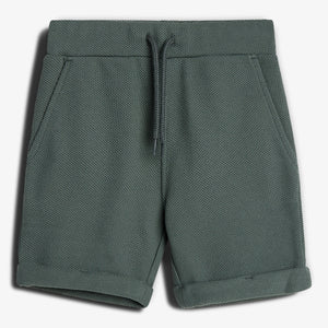 Eine grüne, kurze Hose mit Kordelzug liegt flach auf einem weißen Hintergrund. Sie hat aufgesetzte Taschen und umgeschlagene Beinenden, aus strukturiertem Stoff.