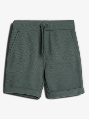 Eine grüne, kurze Hose mit Kordelzug liegt flach auf einem weißen Hintergrund. Sie hat aufgesetzte Taschen und umgeschlagene Beinenden, aus strukturiertem Stoff.