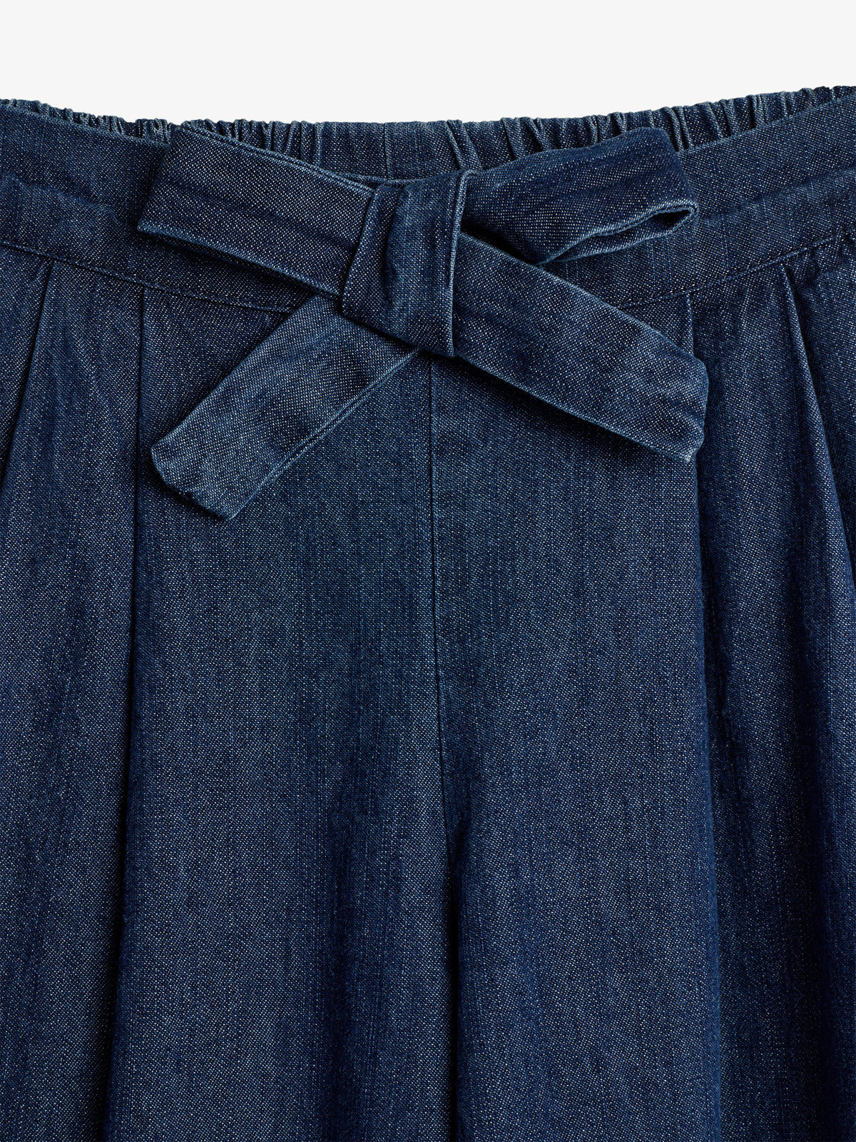 Ein blauer Taillenbund einer Jeanshose ist mit einer angenähten Schleife verziert. Der Stoff ist gerafft, was der Hose ein elegantes und stilvolles Aussehen verleiht.