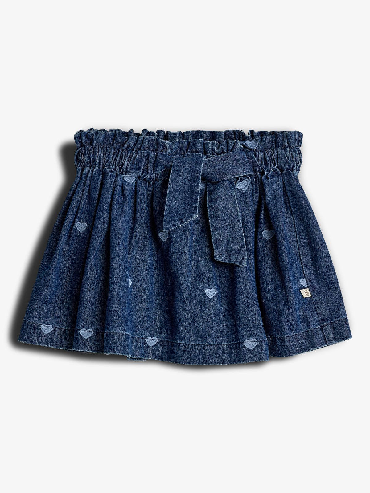 Ein Jeansrock mit elastischem Bund und Schleife. Kleine Herzmotive zieren den Stoff. Der Rock liegt auf einem neutralen Hintergrund. Keine sichtbare Schrift vorhanden.