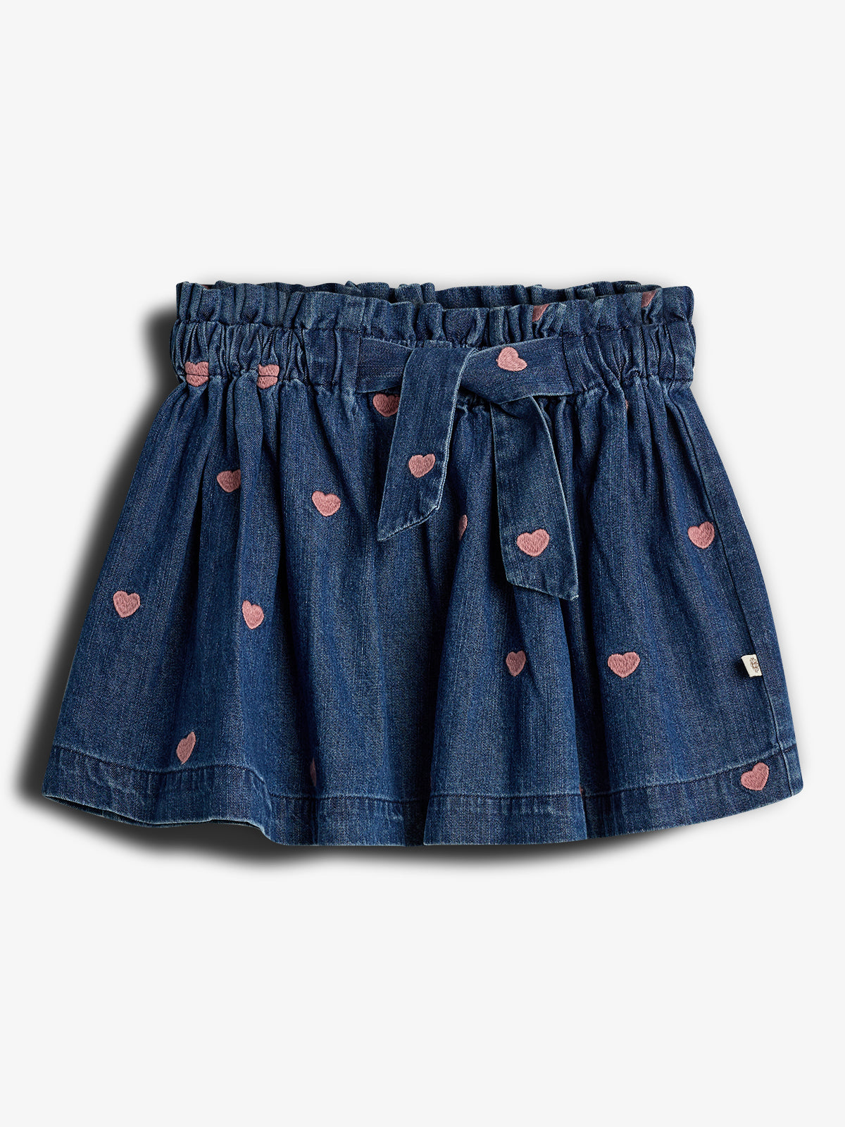 Ein blauer Jeansrock mit rosa herzförmigen Mustern. Der Rock hat einen gerafften Bund mit Schleife und wird vor neutralem Hintergrund dargestellt. Keine weiteren Objekte im Bild.