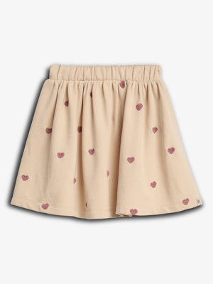 Ein beiger Kinderrock mit rosa Herzmustern verteilt. Der Rock hat einen elastischen Bund und fällt locker. Der Hintergrund ist neutral ohne weitere Dekoration.