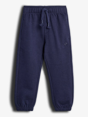 Eine dunkelblaue Jogginghose liegt flach, mit elastischem Bund und Kordelzug, in einem hellen Hintergrund. Sie hat seitliche Taschen und ein dezentes kleines Logo auf dem Bein.