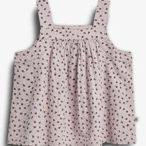 Ein rosa Sommerkleid mit breiten Trägern, verziert mit einem Muster aus kleinen braunen Blumen, hängt lose in einem neutralen, weißen Hintergrund.