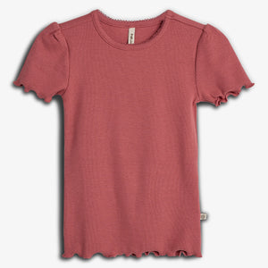 Rosa T-Shirt mit welligen Ärmeln und Saum, flach präsentiert auf weißem Hintergrund. Ein Etikett "Müsli" ist im Nackenbereich sichtbar.