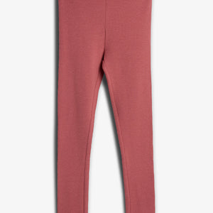 Rote Leggings hängen glatt, mit gewelltem Saum. Hintergrund ist neutral grau, was die Textur und Farbe der Leggings hervorhebt.