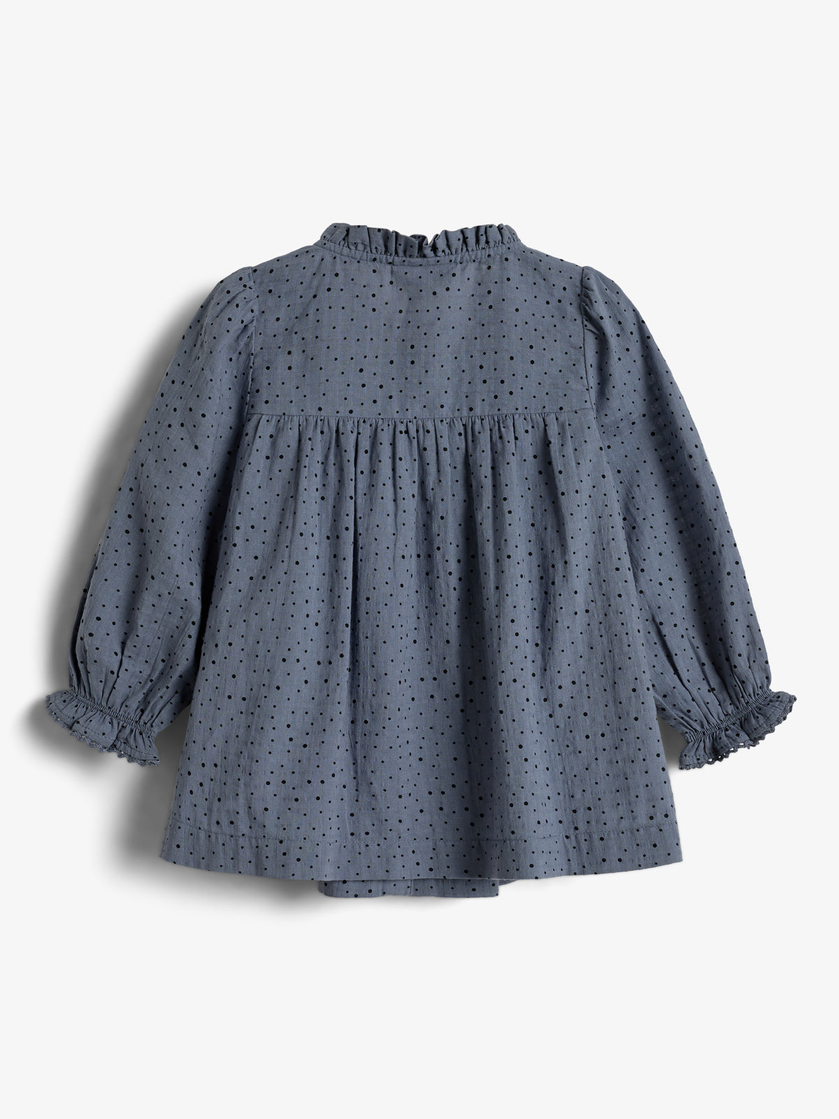 Ein graues, langärmeliges Kinderkleid mit Rüschenärmeln und Kragen weist ein Punktemuster auf. Es liegt flach auf einer weißen Fläche.