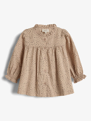 Bluse mit Punkten, hängt unverändert; Umgebung ist einfarbiger Hintergrund. Text auf Schild: "Manufacture 9-12M".