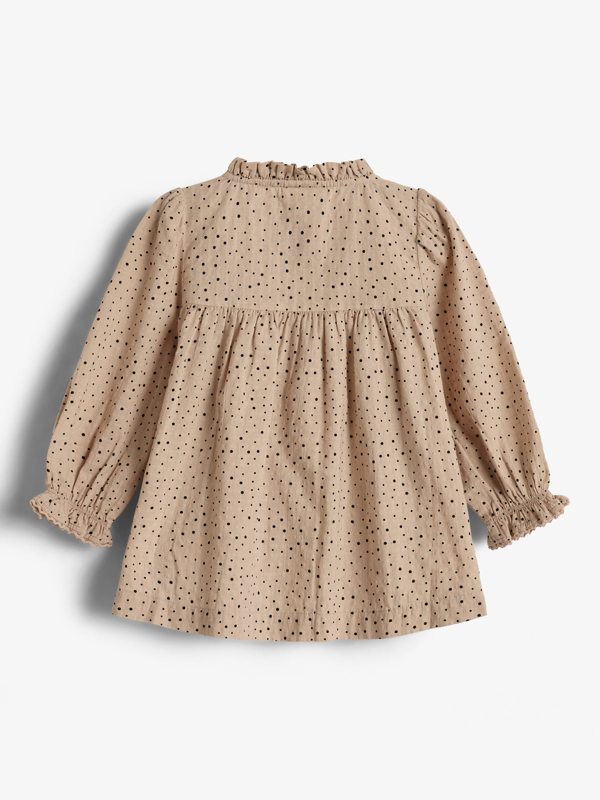 Ein beige-gemustertes Kleid mit langen Ärmeln und Rüschen am Kragen hängt locker. Es ist mit schwarzen Punkten bedeckt und befindet sich vor einem weißen Hintergrund.