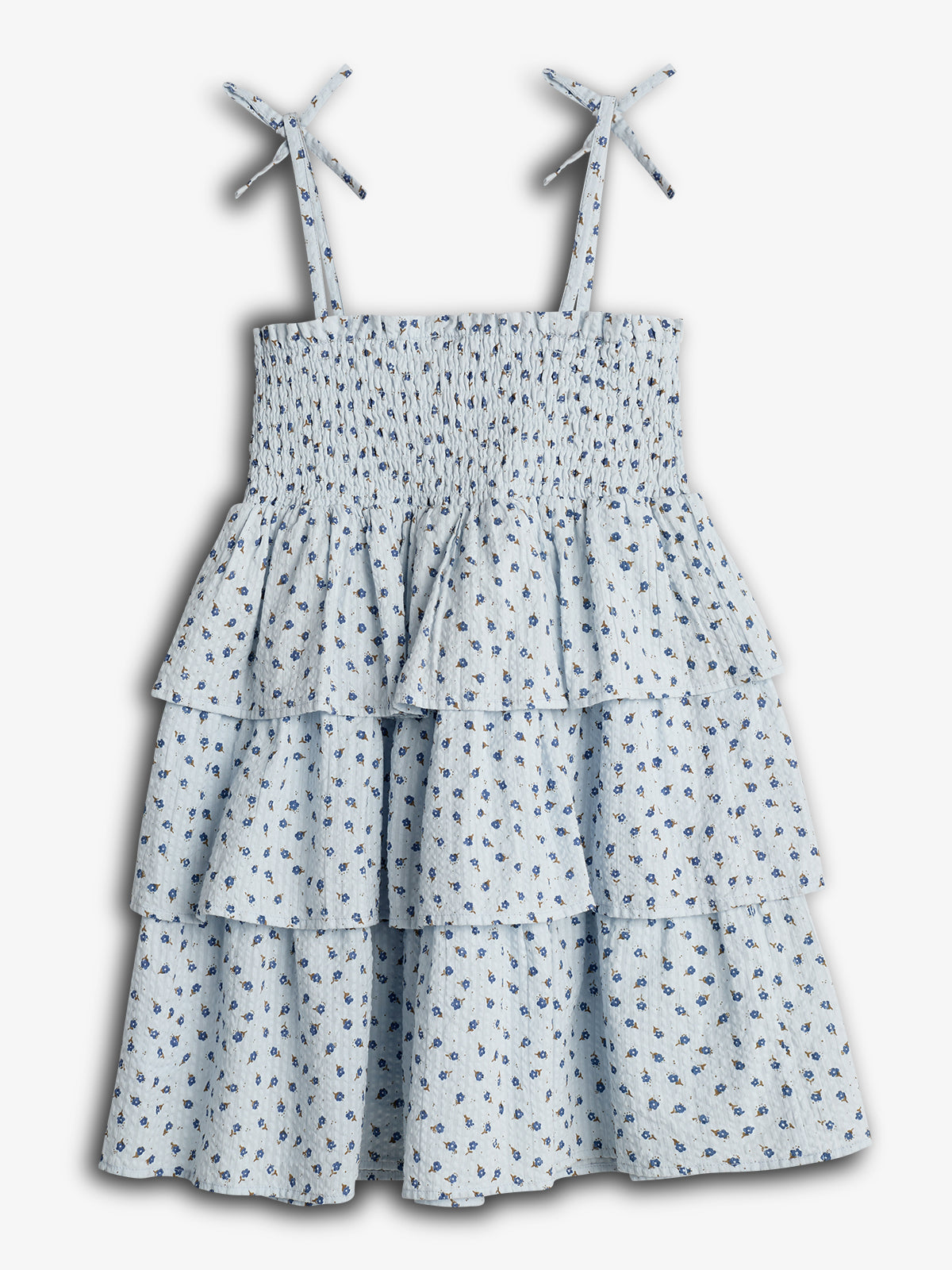 Kleid mit Rüschen liegt flach auf weißem Hintergrund. Es hat einen hellblauen Stoff mit kleinen Blumenmustern und verstellbaren Trägern, die in Schleifen gebunden sind.