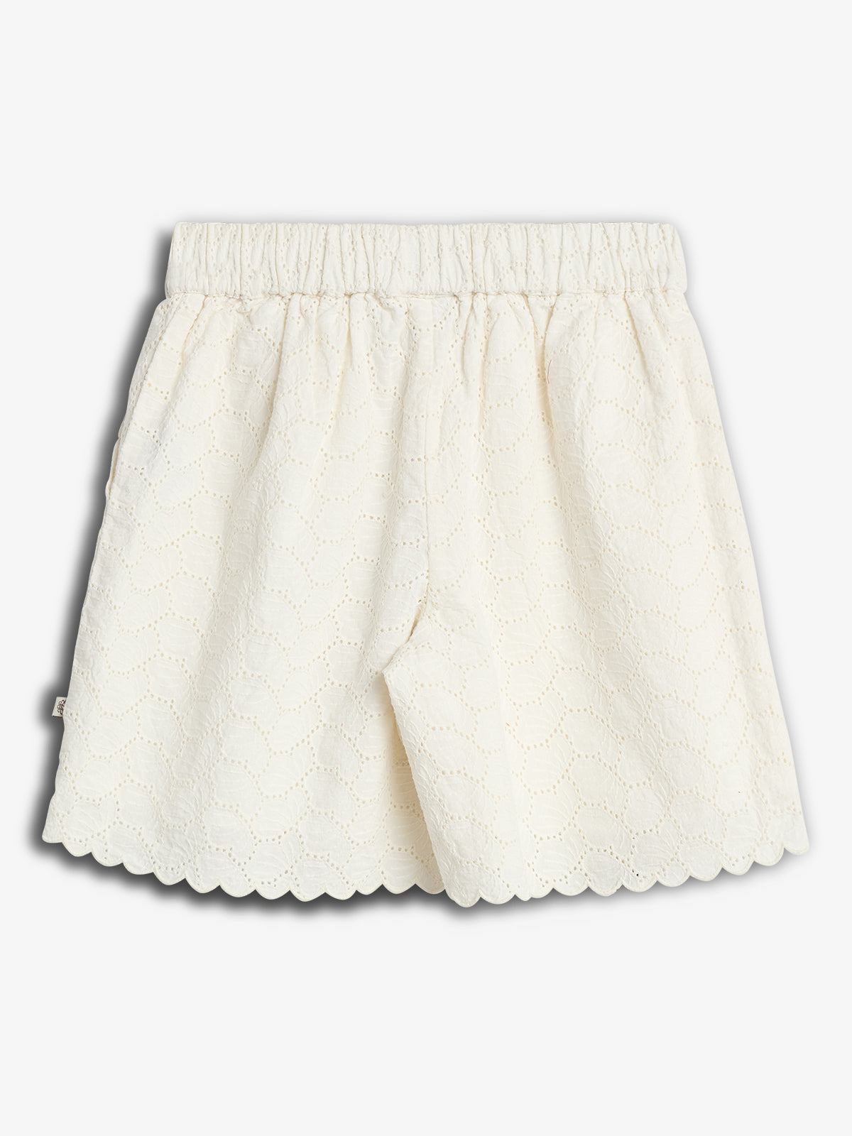 Weiße, weit geschnittene Shorts mit elastischem Bund und Lochstickmuster, in einem schlichten Studio mit weißem Hintergrund dargestellt.