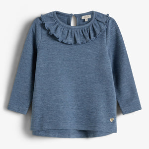 Der Pullover hat lange Ärmel und einen gewellten Kragen. Er besteht aus blauem Stoff. Im unteren Bereich befindet sich ein kleines goldenes Herzsymbol. Hintergrund ist schlicht weiß.