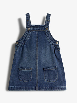 Jeanskleid mit Trägern und vier Knöpfen. Es hat zwei aufgesetzte Taschen vorne. Der Stoff ist dunkelblau, leicht verwaschen. Hintergrund ist ein neutraler, heller Ton.