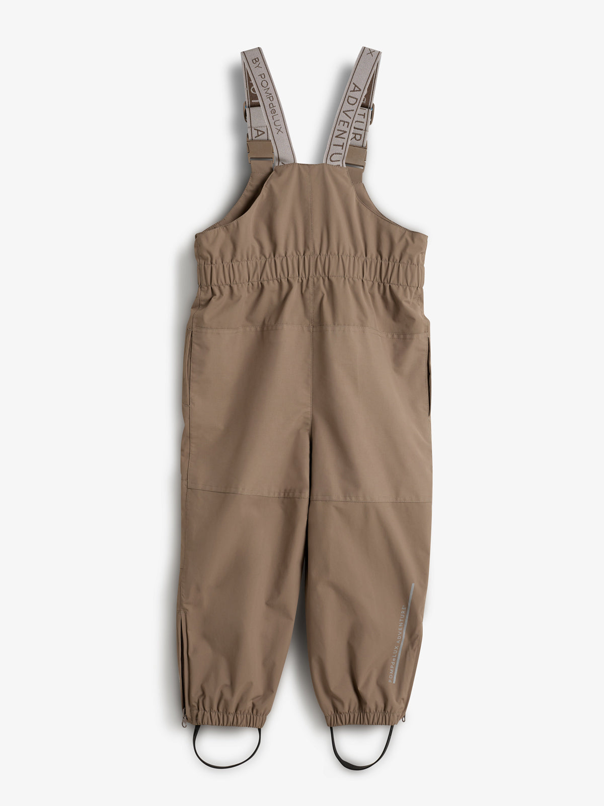Eine beige Kinderlatzhose mit verstellbaren Trägern liegt flach, gefasst von elastischen Beinabschlüssen. Auf den Trägern steht "ADVENTURE BY POWDERFLEX". Im Hintergrund ist eine weiße Oberfläche.