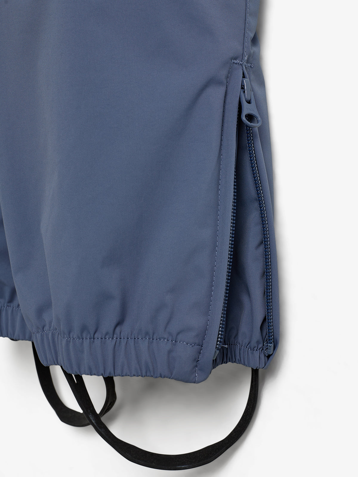 Dunkelblaue Outdoor-Jacke mit Reißverschluss auf der Seite und elastischem Saum. Zwei schwarze Bänder hängen darunter. Weißer Hintergrund.