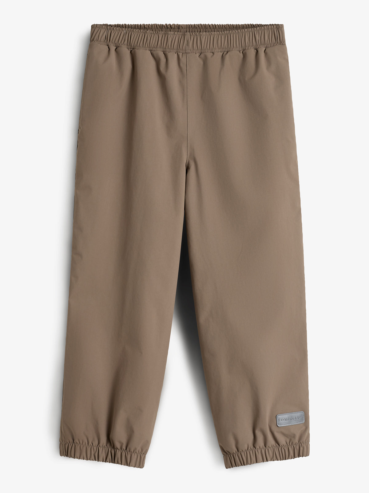 Eine braune, knöchellange Hose mit elastischem Bund und Beinabschlüssen liegt flach ausgebreitet auf einem weißen Hintergrund. Ein graues Etikett mit der Aufschrift "POM POMPS" befindet sich am unteren Rand.