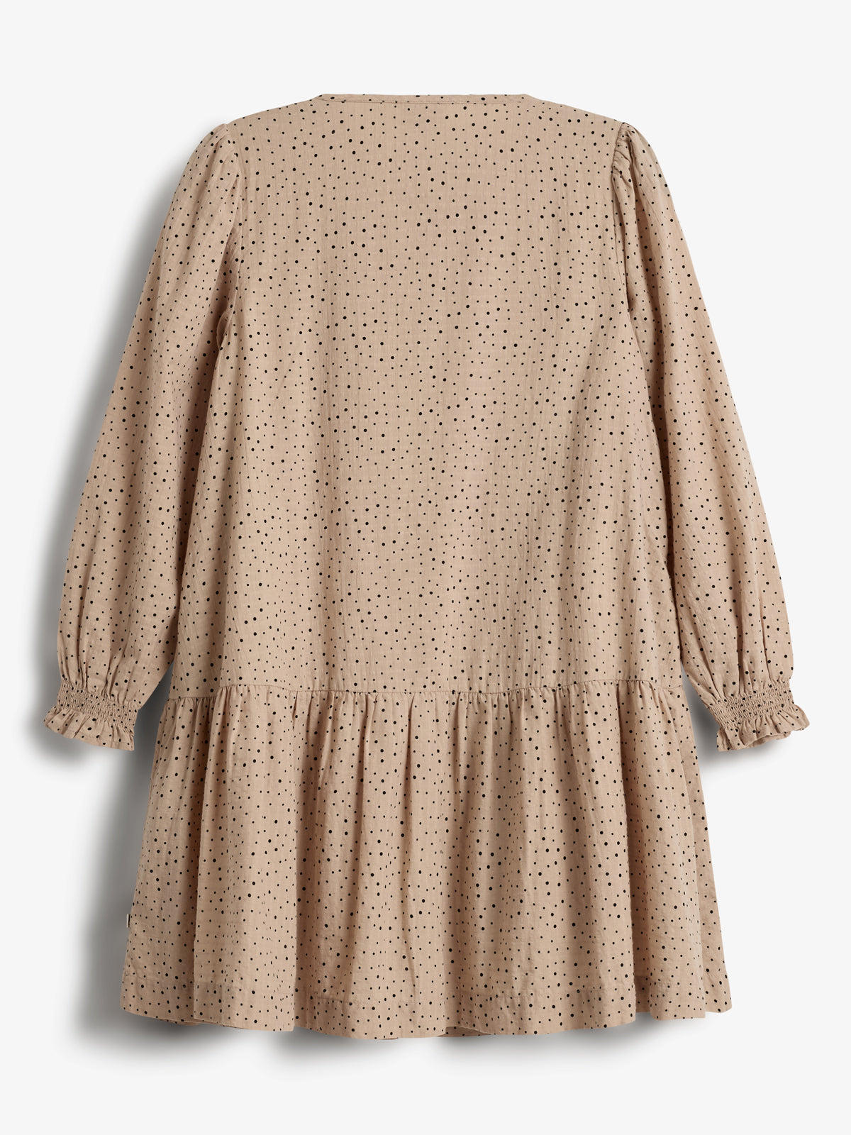 Ein beigefarbenes Kleid mit schwarzen Punkten hängt vor einem weißen Hintergrund. Es hat lange Ärmel mit gerüschten Manschetten und einen ausgestellten Rock.